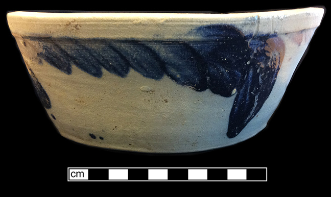 Grey bodied salt glaze stoneware bowl with cobalt decoration. Flat base, sloping sides in a pan form more common before 1860 (Greer 1981:97); Rim diameter:  9.50”, Vessel height:  3.75”, from 18BC33.